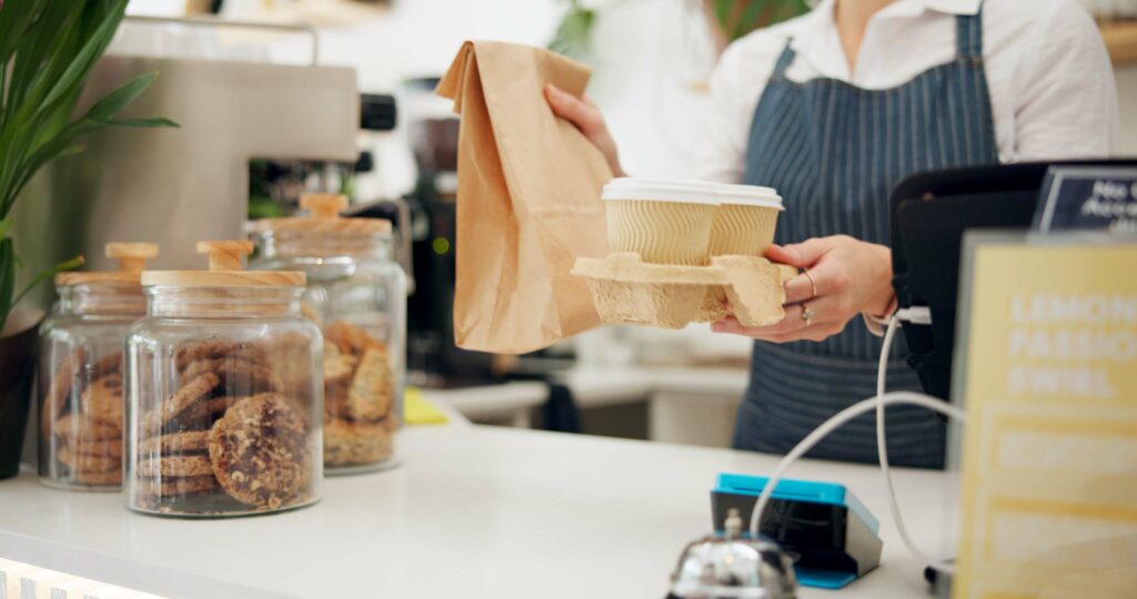 A café or takeaway counter displaying food served in eco friendly takeaway containers made from bagasse, kraft paper, or compostable materials.